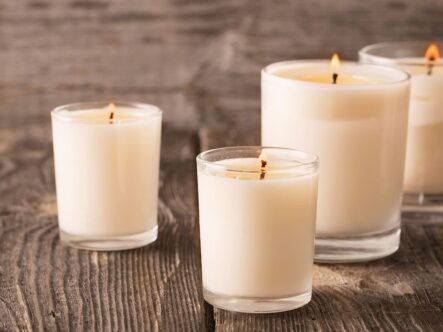 four scented candles on a wooden table in picture.